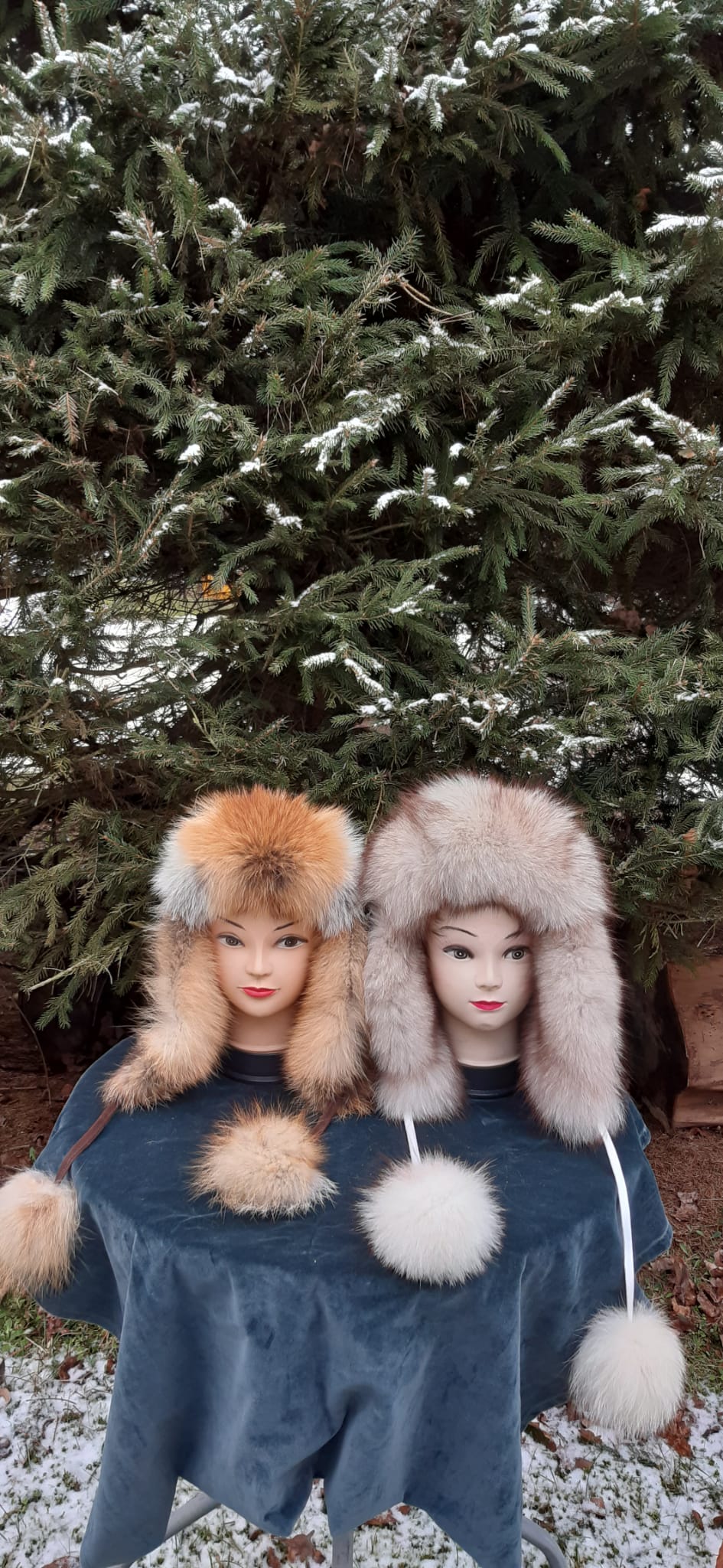 Zwei Fuchspelzmützen mit Ohrenklappen auf Büsten im Winter